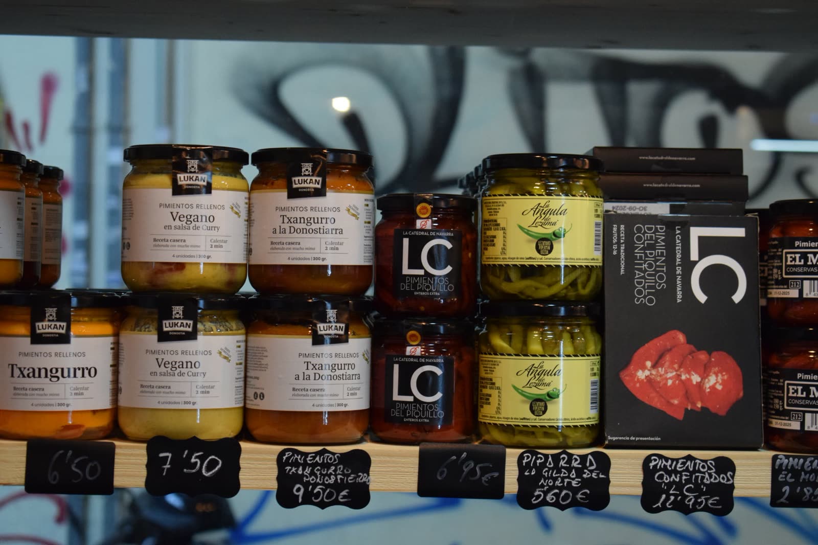 Estanterías del colmado con conservas gourmet y pizarras de precios