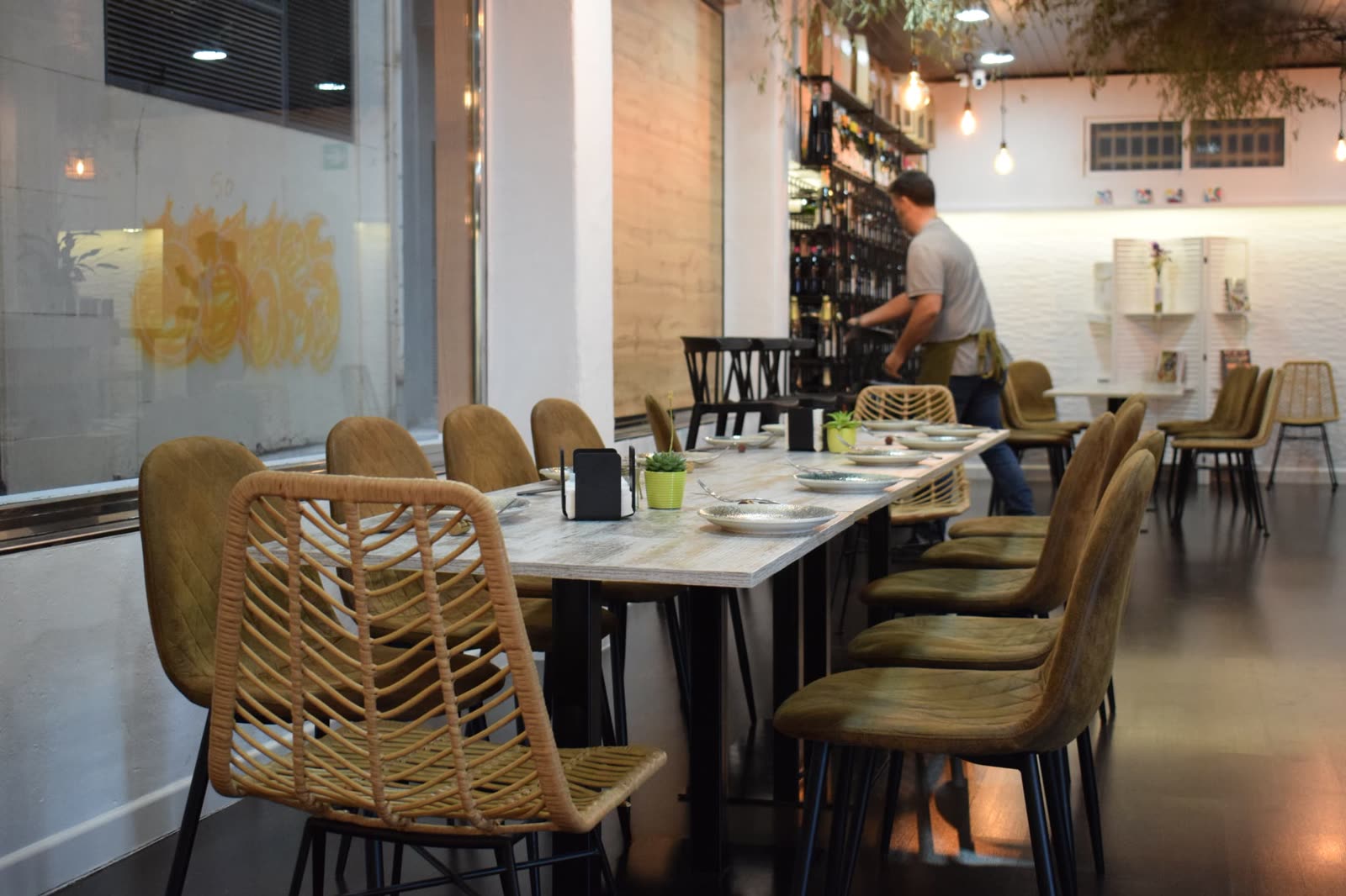 Sala de Gaia con mesa larga, sillas de fibra natural y bodega al fondo